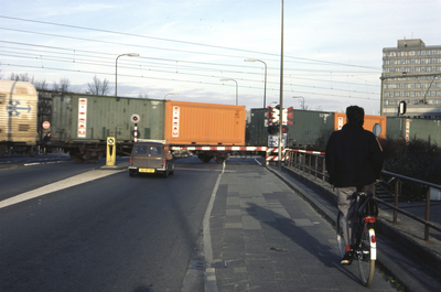 858028 Gezicht op de spoorwegovergang in de Mr. Tripkade te Utrecht, tijdens het passeren van een containertrein.